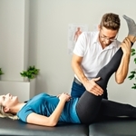 Physical therapist assisting a woman with hamstring stretching during a functional mobility assessment.